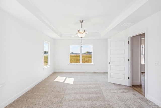 carpeted spare room with a tray ceiling and ceiling fan