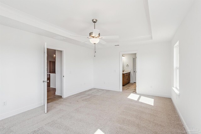 empty room featuring ceiling fan, plenty of natural light, a tray ceiling, and light carpet