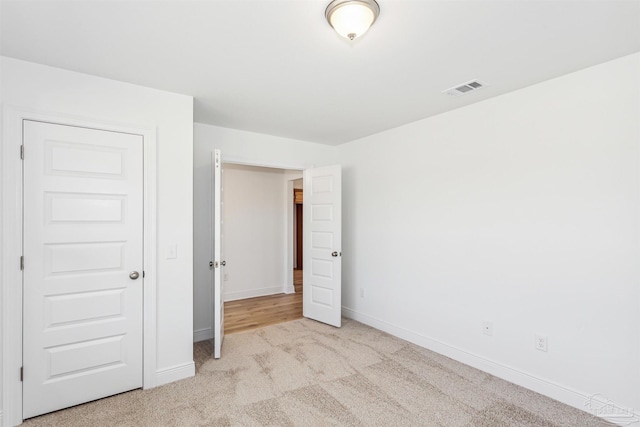 unfurnished bedroom with light carpet and a closet