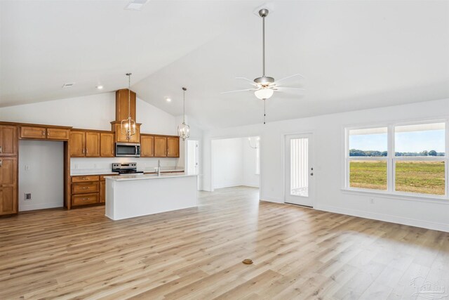 kitchen featuring an island with sink, hanging light fixtures, ceiling fan, stainless steel appliances, and light hardwood / wood-style flooring