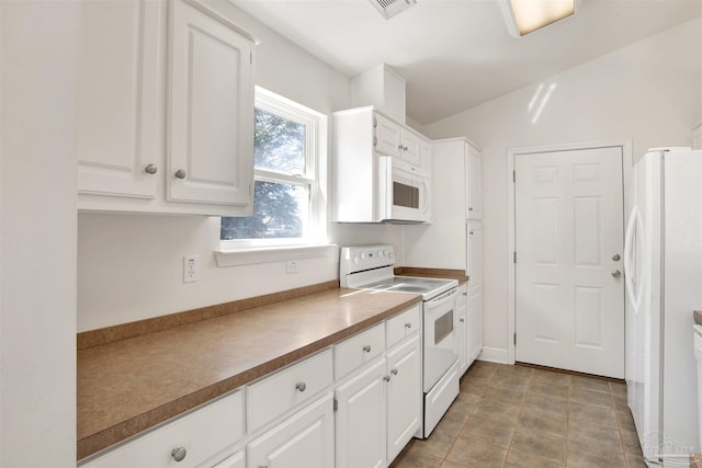 kitchen with tile patterned flooring, white appliances, and white cabinets