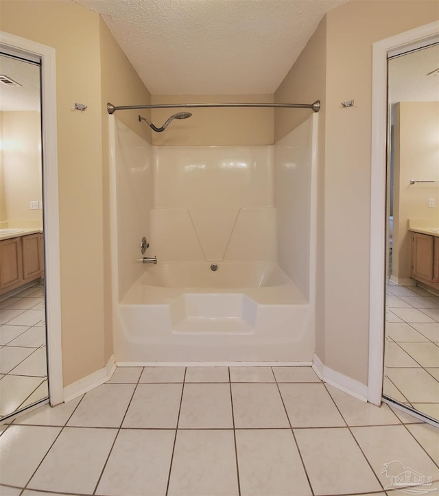 bathroom featuring tile patterned flooring, vanity, a textured ceiling, and shower / bath combination