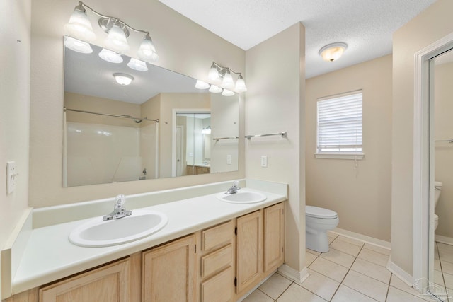 bathroom featuring tile patterned flooring, vanity, a textured ceiling, and toilet