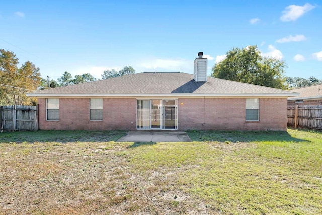 rear view of house featuring a lawn and a patio