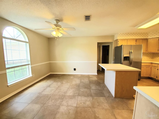 kitchen with a kitchen island, light tile patterned floors, ceiling fan, and stainless steel fridge with ice dispenser