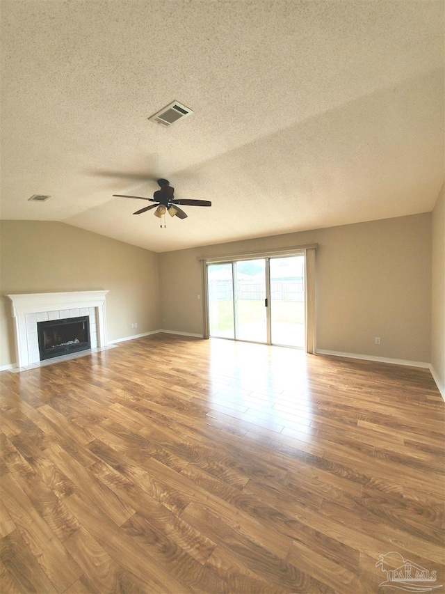 unfurnished living room with a fireplace, wood-type flooring, a textured ceiling, and vaulted ceiling