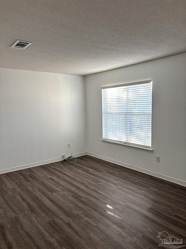 empty room with a textured ceiling and dark hardwood / wood-style flooring