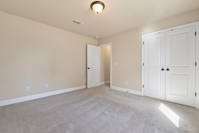 unfurnished bedroom featuring light carpet and a closet