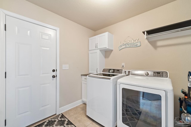 laundry area featuring cabinets, light tile patterned floors, a textured ceiling, and washing machine and clothes dryer