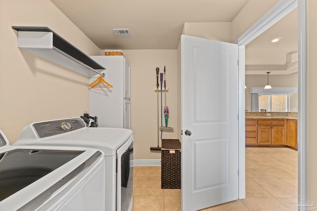 washroom with cabinets, light tile patterned floors, and washer and clothes dryer