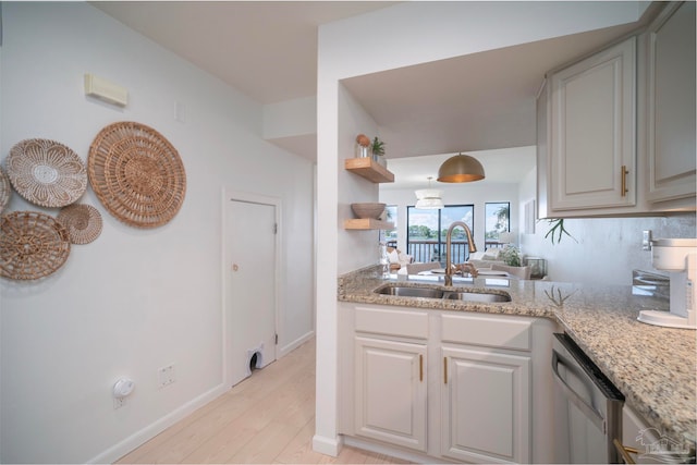 kitchen featuring light stone countertops, sink, dishwasher, white cabinets, and light hardwood / wood-style flooring