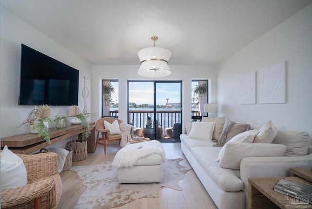 living room featuring light hardwood / wood-style flooring, a water view, and an inviting chandelier