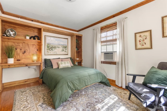 bedroom featuring cooling unit, crown molding, baseboards, and wood finished floors