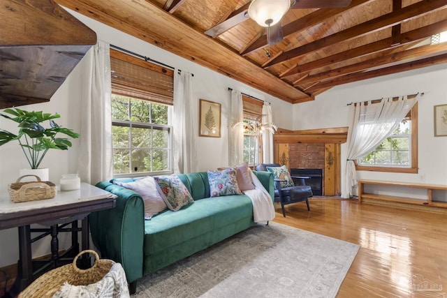 living area featuring a fireplace, lofted ceiling with beams, a ceiling fan, wood finished floors, and wooden ceiling