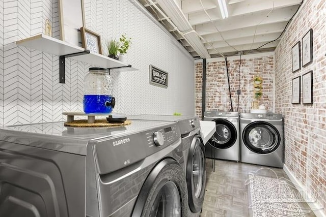 laundry area with laundry area, independent washer and dryer, and brick wall