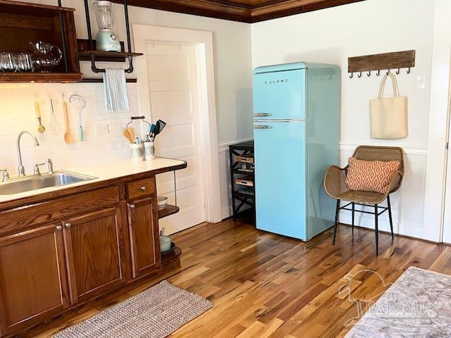 kitchen with a sink, light countertops, backsplash, freestanding refrigerator, and dark wood finished floors