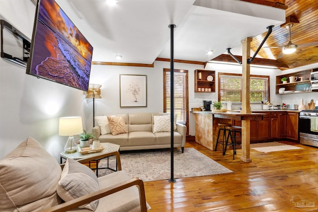 living area featuring ceiling fan, light wood-style flooring, and crown molding