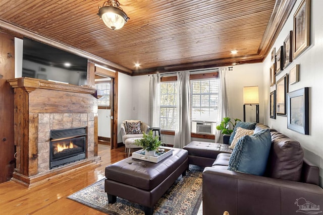 living area featuring a tile fireplace, wooden ceiling, crown molding, and wood finished floors