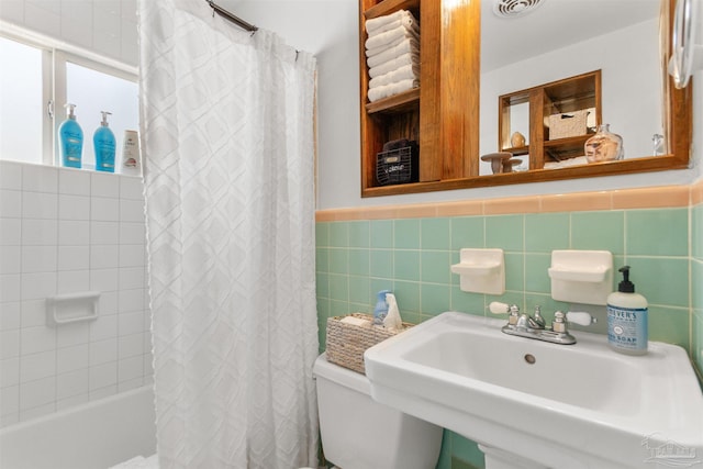 bathroom featuring visible vents, a wainscoted wall, a sink, shower / bath combination with curtain, and tile walls