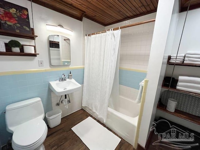 bathroom featuring toilet, wooden ceiling, a wainscoted wall, shower / bath combo with shower curtain, and tile walls