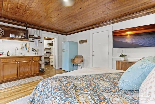 bedroom featuring light wood finished floors, wood ceiling, freestanding refrigerator, a sink, and indoor wet bar