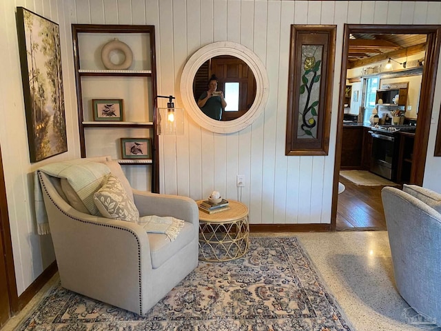 living area with speckled floor, built in shelves, and baseboards