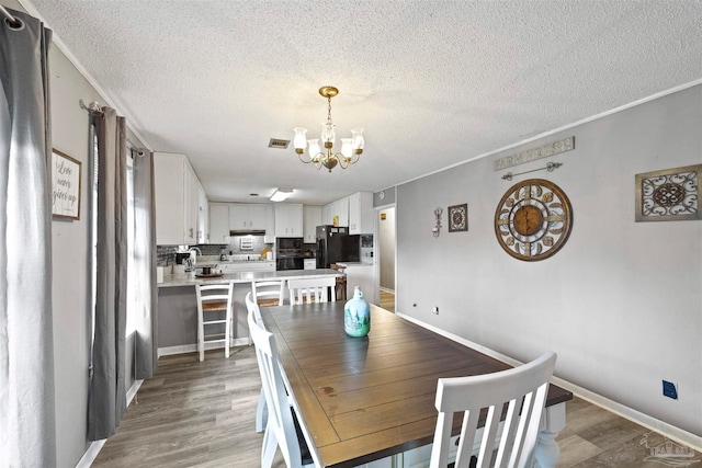 dining room featuring hardwood / wood-style floors, crown molding, a textured ceiling, and a chandelier