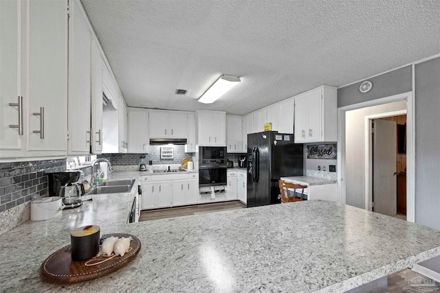 kitchen featuring kitchen peninsula, white cabinets, black appliances, and sink