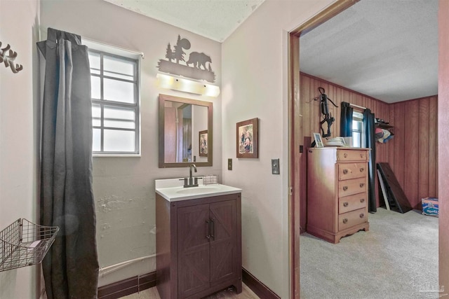 bathroom with vanity, wood walls, and a textured ceiling