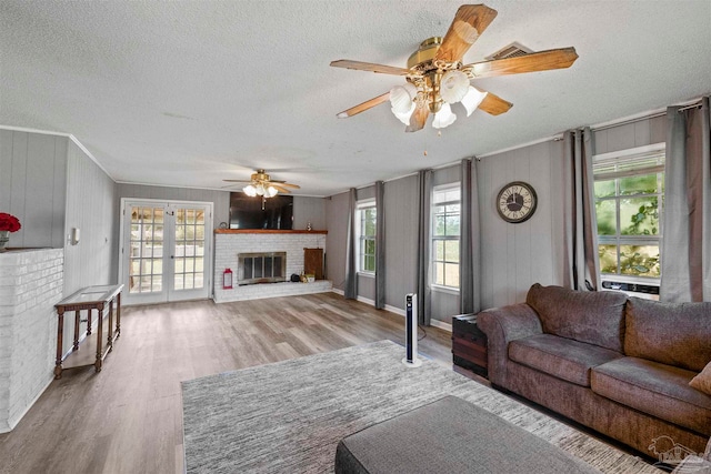 living room featuring a wealth of natural light, a brick fireplace, and light wood-type flooring