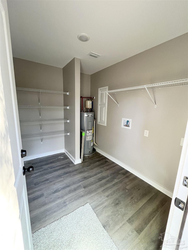 clothes washing area with dark hardwood / wood-style flooring, electric water heater, and washer hookup