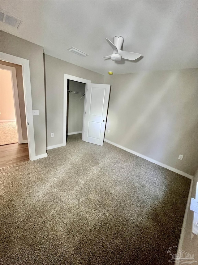 unfurnished bedroom featuring a walk in closet, ceiling fan, a closet, and carpet