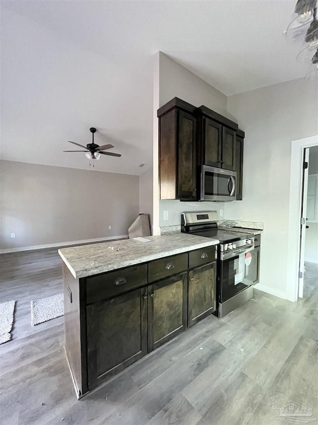 kitchen featuring ceiling fan, stainless steel appliances, kitchen peninsula, dark brown cabinets, and light wood-type flooring