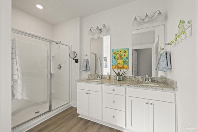 bathroom with vanity, hardwood / wood-style floors, and a shower with door