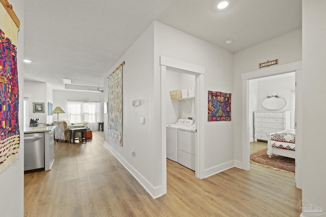 corridor with a textured ceiling, washer and dryer, and light wood-type flooring