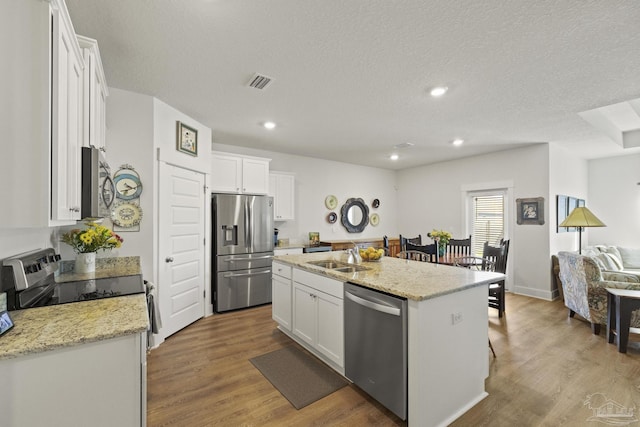 kitchen featuring light stone counters, stainless steel appliances, a kitchen island with sink, and white cabinets