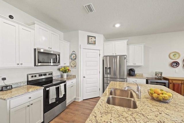 kitchen featuring white cabinetry, appliances with stainless steel finishes, sink, and light wood-type flooring