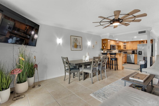 dining area with ceiling fan, light tile patterned floors, and crown molding