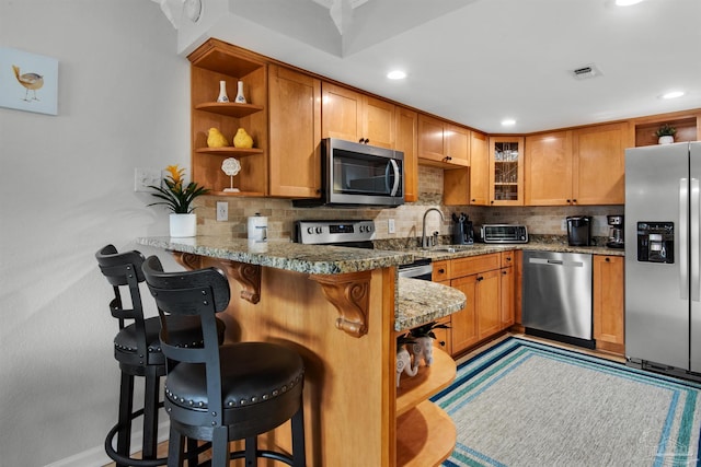 kitchen featuring stainless steel appliances, decorative backsplash, sink, kitchen peninsula, and a breakfast bar area