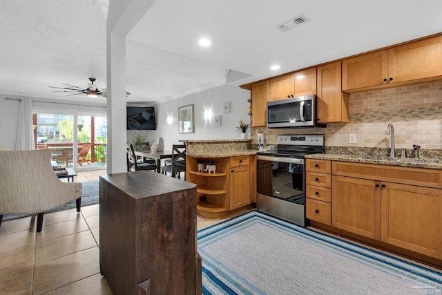 kitchen featuring kitchen peninsula, stainless steel appliances, tasteful backsplash, light stone countertops, and sink