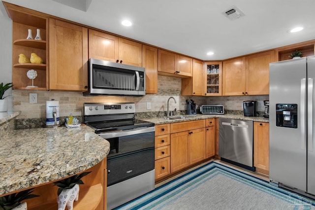 kitchen featuring light stone countertops, appliances with stainless steel finishes, decorative backsplash, and sink