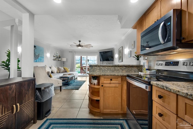 kitchen featuring ceiling fan, light tile patterned flooring, ornamental molding, stainless steel appliances, and stone countertops