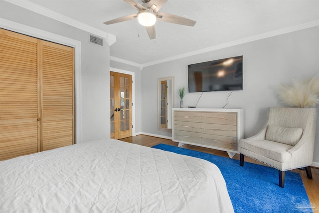 bedroom with ceiling fan, dark wood-type flooring, ornamental molding, a closet, and french doors