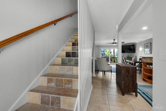 stairs with ceiling fan, tile patterned floors, and ornamental molding