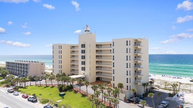 view of building exterior with a beach view and a water view