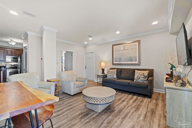 living area featuring visible vents, baseboards, recessed lighting, light wood-style floors, and crown molding