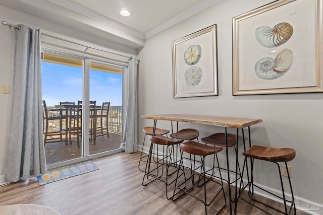 dining space with wood finished floors, baseboards, and ornamental molding