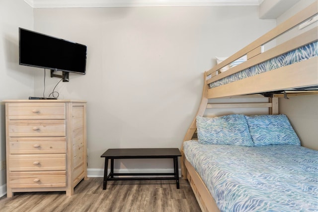 bedroom featuring baseboards, wood finished floors, and ornamental molding