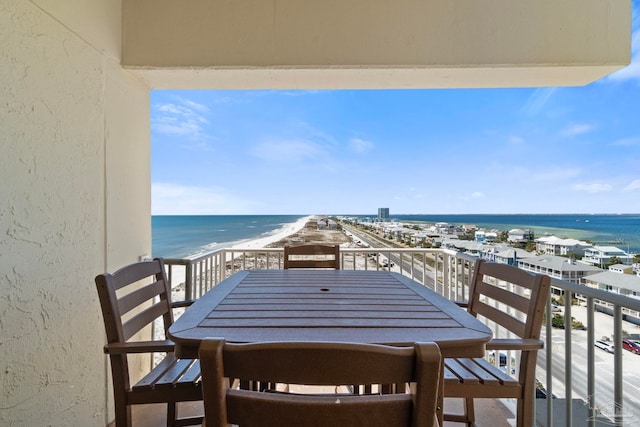 balcony with outdoor dining space, a beach view, and a water view