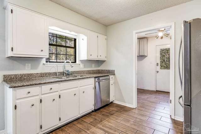 kitchen featuring stainless steel appliances, white cabinetry, sink, and a textured ceiling